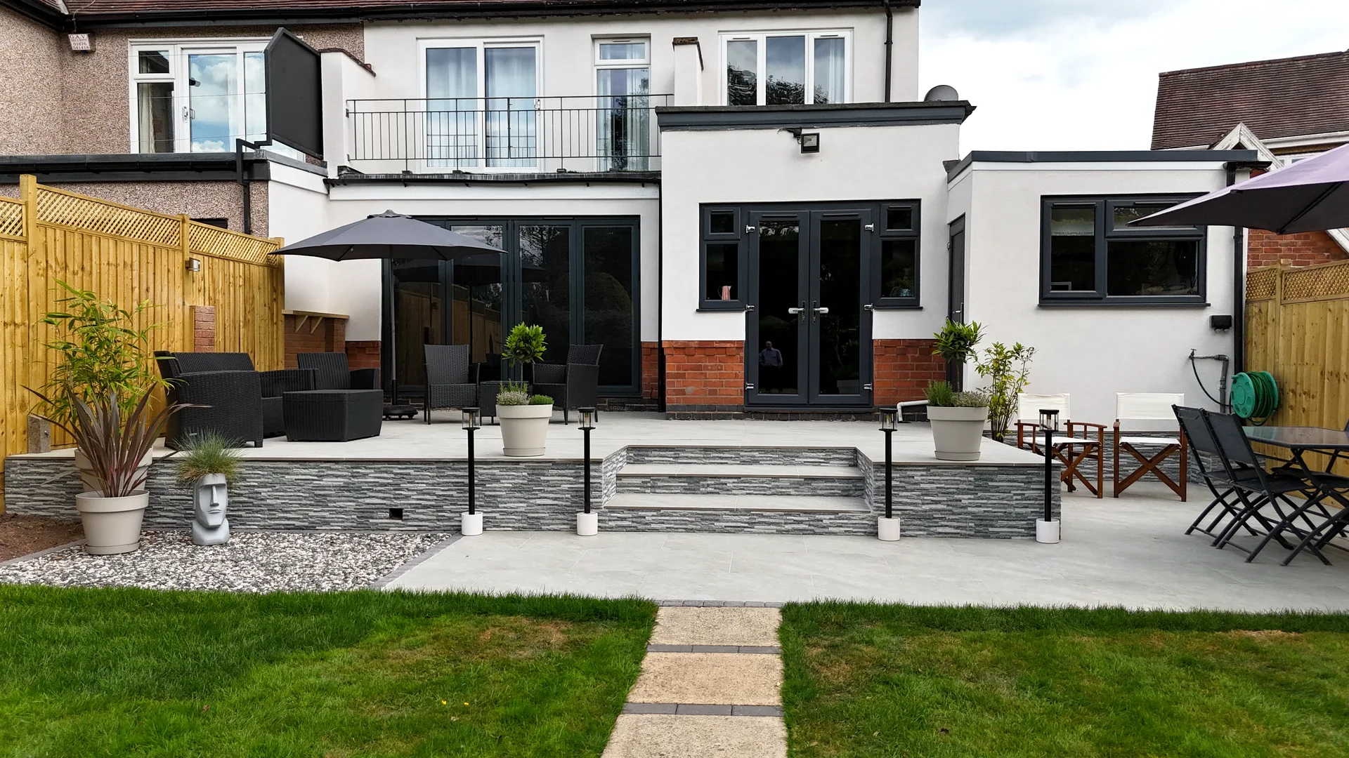 Completed Dna Landscapes garden project with porcelain paving, lawn, steps, and seating area.
